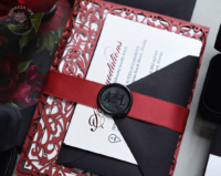 Red Laser Cut Invitations with ornate filigree folder, wrapped in a red satin ribbon with black wax seals