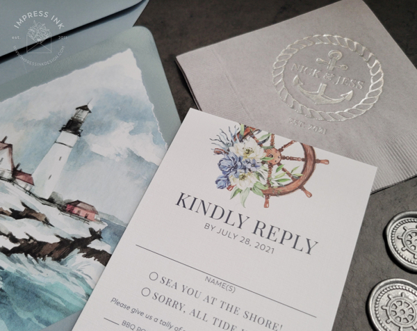 Detail photo of reply cards with blue floral ship wheel, lighthouse envelope liners, and napkins