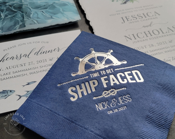 Navy blue napkin with silver foil imprint of a nautical ship wheel