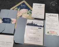 Seattle Skyline Pocket Invitation with city silhouette in shades of navy blue, blush pink floral accents, and gold foil