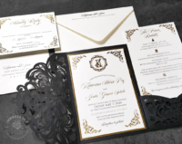 Gold Ornate Monogram Invitation with gold foil flourishes mounted inside a black laser cut pocket folder in a filigree pattern