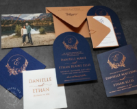 Navy Copper Arch Invitation with floral wreath monogram in copper foil on matte navy cardstock, terracotta colored envelopes