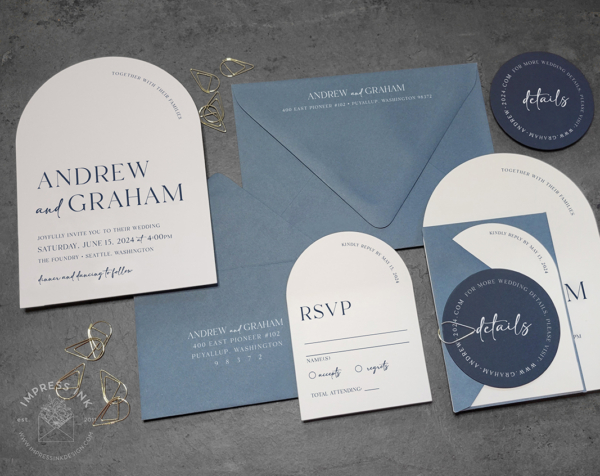 Modern Blue Arch Invitation with white arch cards, slate blue envelopes, navy circle details cards, and gold teardrop paperclips