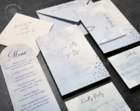 Silver Whimsical Watercolor Invitation with light blue textured background and silver foil imprint with confetti embellishment on the corners.